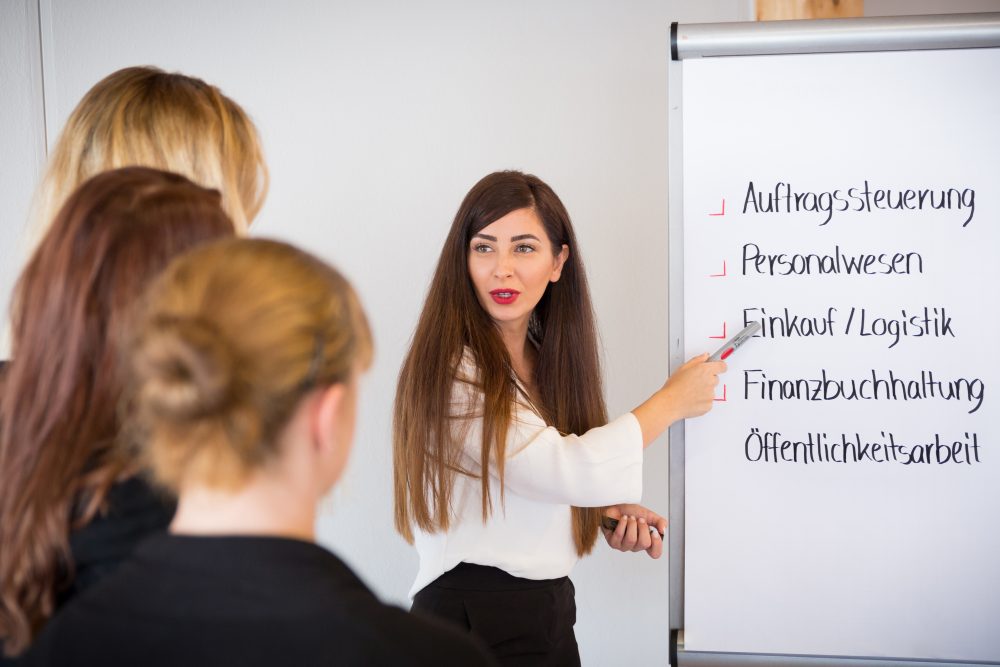 eine junge Frau erklärt Punkte am Flipchart