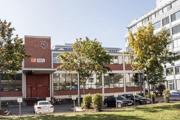 Blick auf das Backsteingebäude der IWL München mit grünen Bäumen davor