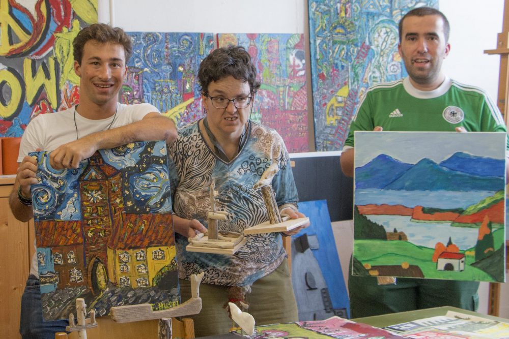 Eine Künstlergruppe bestehend aus drei Männern und einer Frau zeigen ihre Kunstwerke in Form von Bildern und Skulpturen