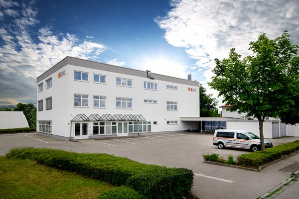 Gebäude der IWL Landsberg in der Graf-Zeppelin-Straße mit einem hellblauen Himmel und weißen Wolken am Himmel