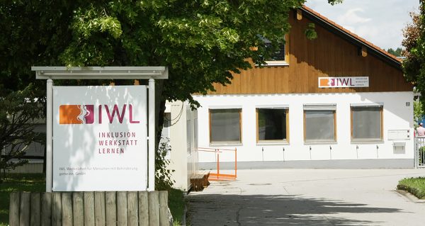 Das Gebäude der IWL Machtlfing mit einem großen Schild mit dem IWL Logo