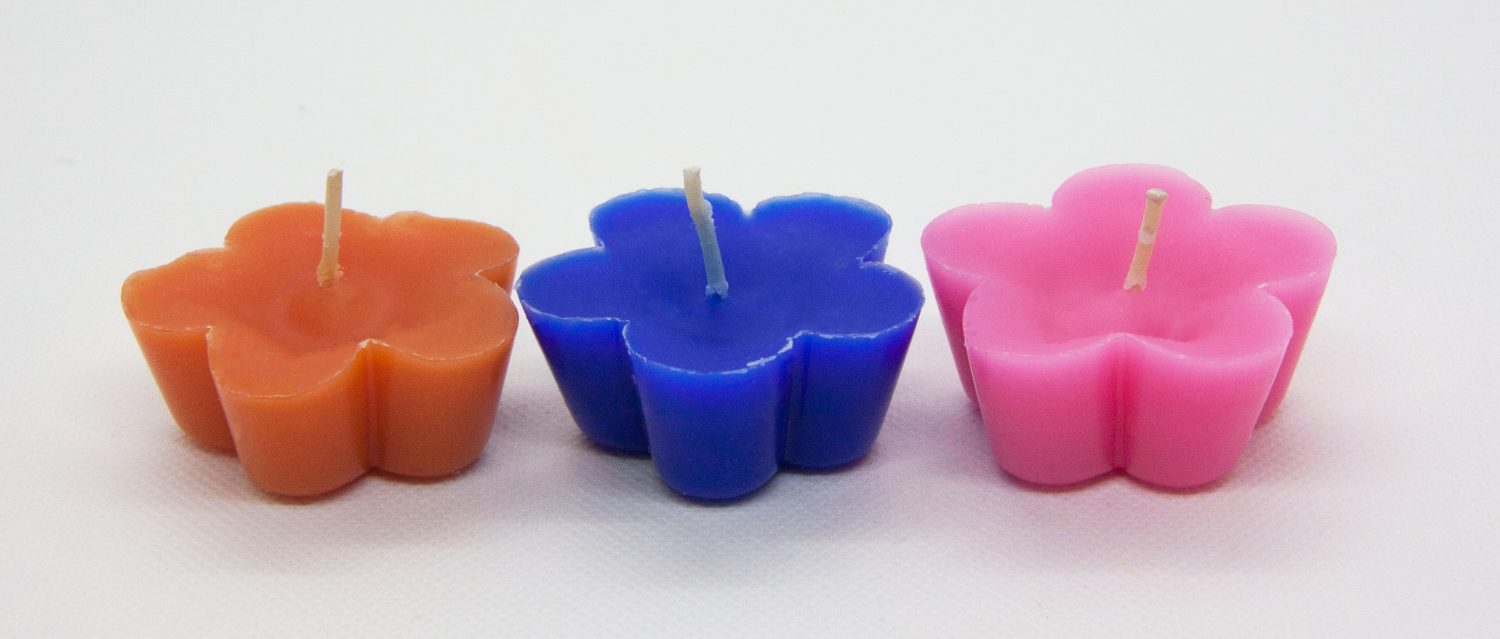 Kleine Schwimmkerzen oder Teelicher in drei knallbunten Farben: orange, blau und pink